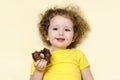 Happy child tastes the sweetness. girl eating, biting delicious chocolate donut with an appetite and having fun, on yellow backgro