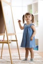 Happy cute toddler girl drawing or writting with marker pen on a blank whiteboard at home, preschool, daycare or Royalty Free Stock Photo