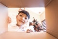 The happy child unpacking  opening the carton box  and looking inside. The little Asian kid unboxing gift inside view Royalty Free Stock Photo