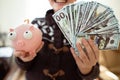 A happy child with a wad of money in his hands. Eaten money collected in the piggy bank. Cashing coins from the piggy