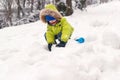 Happy child in warm clothing playing with snow. Child in warm clothing in winter. Kid making snowballs on winter cold day. Child p Royalty Free Stock Photo