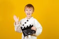 Happy child in white kimono making video or movie. Little actor over yellow background. Kids sport, hobbies and leisure concept