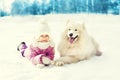 Happy child with white Samoyed dog lying on snow in winter Royalty Free Stock Photo