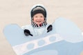 Happy child in winter fashion clothes posing with a toy airplane in the courtyard of his village house. First snow, family, tradit