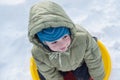 Happy child in winterwear laughing while playing in snowdrift