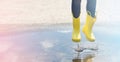 Happy child in yellow wellington boot jumps in a puddle of water after rain. Cheerful baby on a summer sunny day Royalty Free Stock Photo