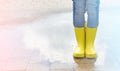 Happy child in yellow wellington boot jumps in a puddle of water after rain. Cheerful baby on a summer sunny day Royalty Free Stock Photo