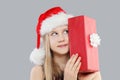 Happy child young girl in Santa hat holding red gift present on gray background Royalty Free Stock Photo