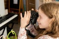 Happy child young school age girl taking photos with her professional large DSLR camera at home, smiling face closeup, side view. Royalty Free Stock Photo