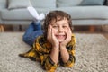 Happy childhood. Close up portrait of cheerful little boy smiling to camera, lying on floor at home Royalty Free Stock Photo