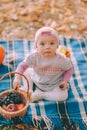 Happy childhood. A cute baby girl in a pink beanie sits on a blue blanket with a basket full of fruits Royalty Free Stock Photo