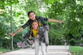 Happy childhood friends have fun piggybacking in park on summer day, holidays