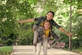 Happy childhood friends have fun piggybacking in park on summer day, holidays