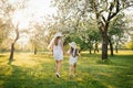 daughter holds her mother\'s hand and runs with her through the spring blooming garden