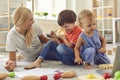 Happy family mother and children sitting on floor and playing together at home Royalty Free Stock Photo