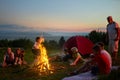Happy children with adult instructor sitting around campfire in evening outdoor. Royalty Free Stock Photo