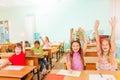 Happy children with arms up sitting in classroom Royalty Free Stock Photo