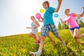 Happy children with balloons run in green field Royalty Free Stock Photo