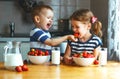 Happy children brother and sister eating strawberries with milk Royalty Free Stock Photo