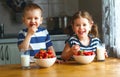 Happy children brother and sister eating strawberries with milk Royalty Free Stock Photo