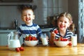 Happy children brother and sister eating strawberries with milk Royalty Free Stock Photo