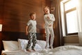 Happy children brother and sister jump on bed in bedroom Royalty Free Stock Photo