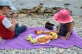 happy children brother and sister sit by the sea, have a picnic, eat fruit, pastries, drink juice and cocktail. Friends