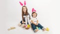 Happy children celebrate Easter. little girls wearing bunny ears enjoying egg hunt. Kids playing with color eggs and flower basket Royalty Free Stock Photo