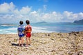 Happy children in colorful hawaiian shirts, enjoying observing the big waves on shore of an island near Mauritius