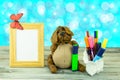 Workplace from child with funny dog is holding a green pencil, colorful pens and an empty frame with butterfly.Happy children day.