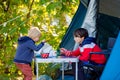 Happy children, eating breakfast in the morning in front of a tent in a campsite in the forest in Norway