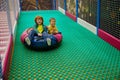 Happy children enjoying tuba ride down on slide at indoor kids playground Royalty Free Stock Photo