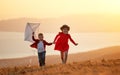 Happy children girl and boy launches a kite at sunset outdoors