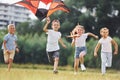 Happy children. Group of kids are running and playing with kite on green field Royalty Free Stock Photo