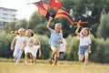 Happy children. Group of kids are running and playing with kite on green field Royalty Free Stock Photo