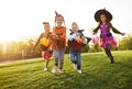 Happy children in Halloween costumes running on lawn