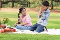 Happy children have a picnic in summer green park garden. Two Asian friends, boy and girl reading book and playing together on a Royalty Free Stock Photo