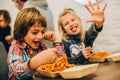 Happy children having fun while eating spaghetti pasta