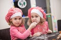 Happy children identical twin sisters tasking biscuits in the kitchen, casual lifestyle photo in real life interior, young family Royalty Free Stock Photo