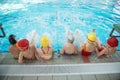 Happy children kids group at swimming pool class learning to swim