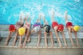 Happy children kids group at swimming pool class learning to swim