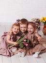 Happy children laugh and cuddle in a room with flowers. Brother and two sisters
