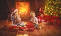 Happy children open Christmas gifts at night at Christmas tree