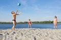 Happy children play with the ball with their parents on the river bank, in the summer season.  Family leisure on the water Royalty Free Stock Photo