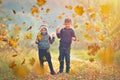 Happy children playing with autumn fallen leaves in park