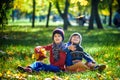 Happy children playing in beautiful autumn park on warm sunny fall day. Kids play with golden maple leaves Royalty Free Stock Photo