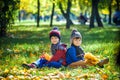 Happy children playing in beautiful autumn park on warm sunny fall day. Kids play with golden maple leaves Royalty Free Stock Photo