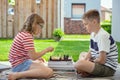 Happy children playing chess on backyard at sunny day while summer holidays Royalty Free Stock Photo