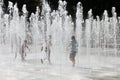 Happy children playing happily in the city fountain on a hot summer day.