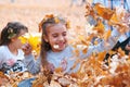 Happy children playing in heap of yellow leaves, posing, smiling and having fun in autumn city park. Bright yellow trees and Royalty Free Stock Photo